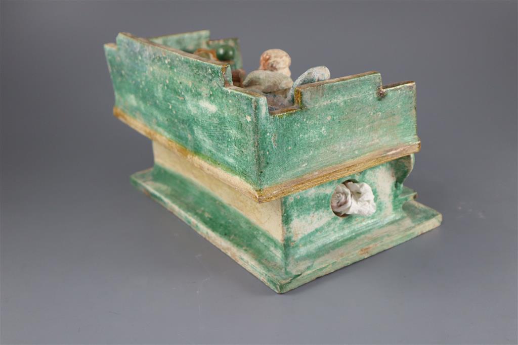 A Chinese Ming sancai model of a day bed and thirteen funeral offerings, 16th century, 29cm wide